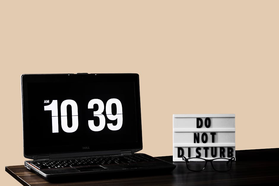 Modern workspace featuring a laptop and 'Do Not Disturb' sign on a wooden desk.