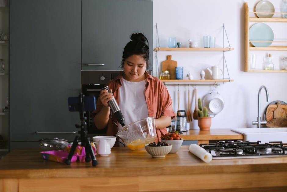 Woman whisking ingredients in a bowl in a modern kitchen setup for a food blog.