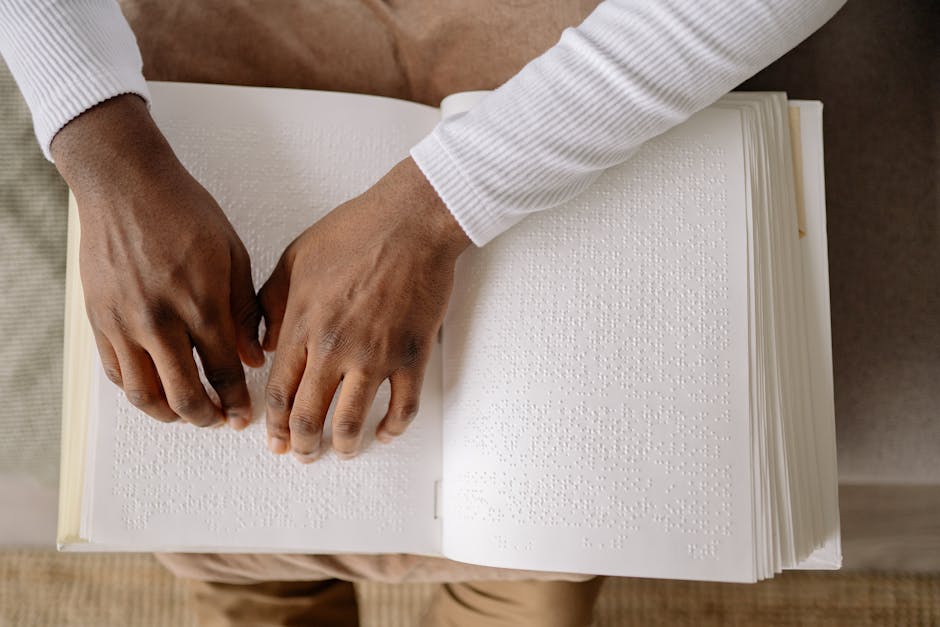 Close-up of hands reading a braille book, symbolizing literacy and accessibility for the visually impaired.